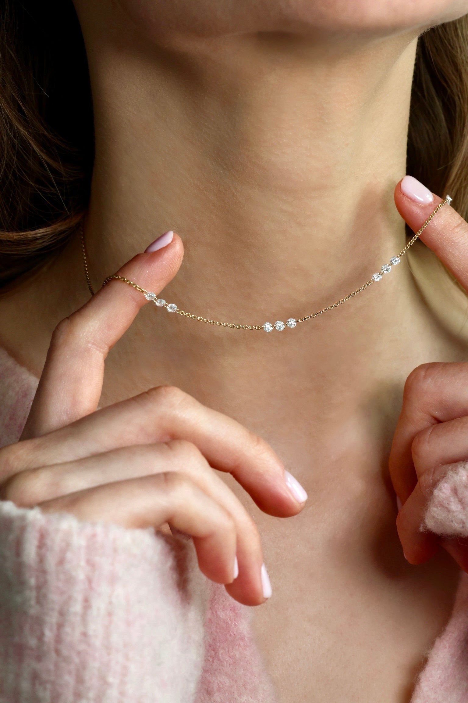 Close-up of a delicate Aurore Lab Grown Diamond necklace being worn, with a soft focus on the background.